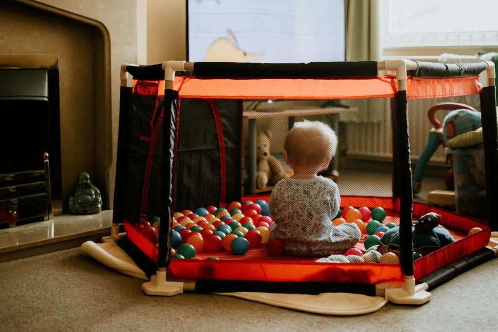 Cute baby boy enjoying a colorful ball pit in a cozy indoor setting.